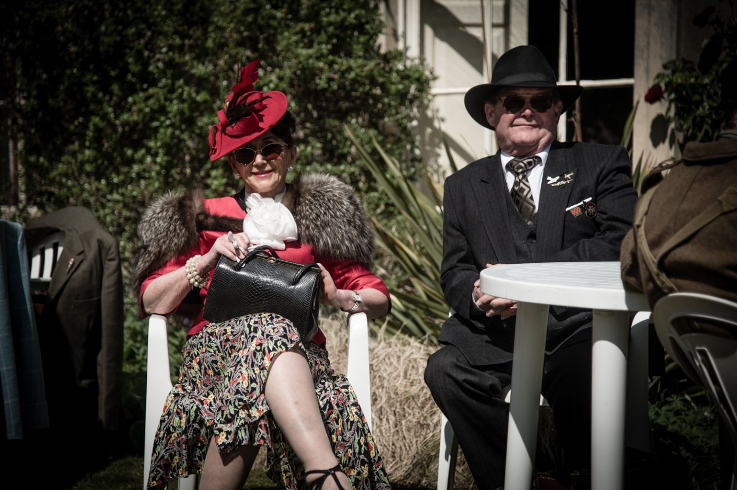 A classically dressed couple sitting enjoying a vintage festival